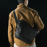 man in black studio wearing black messenger bag across his back