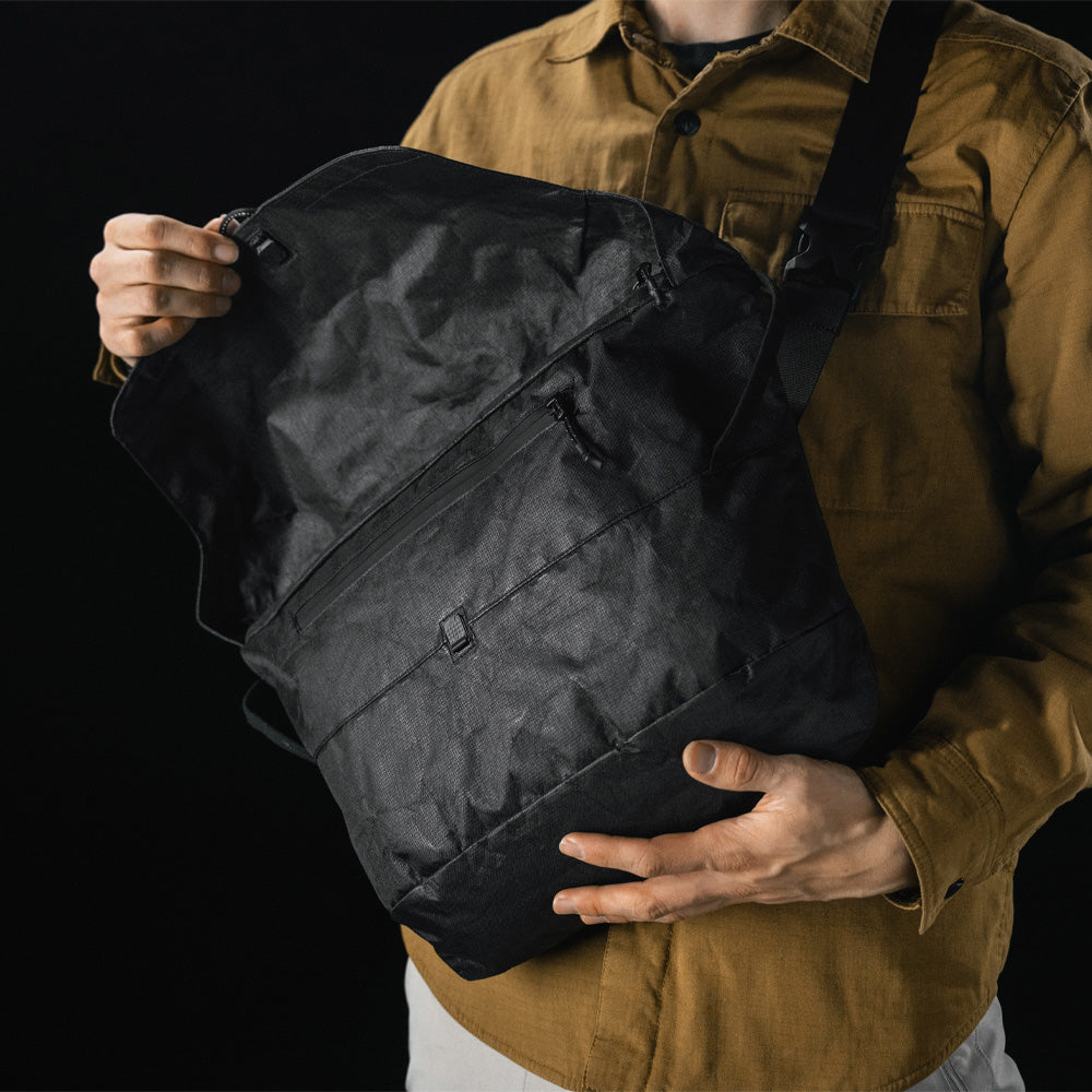 man opening black messenger bag across the front of his body