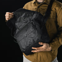 man opening black messenger bag across the front of his body