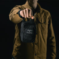 man in black studio holding out packed up sling bag
