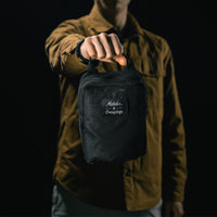 man in black studio holding out packed up messenger bag