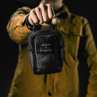 man on black studio background holding packed up white sling bag in mesh bag