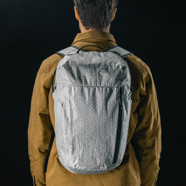 man on black studio background wearing white backpack