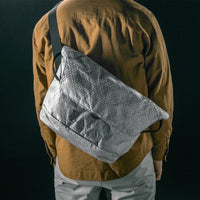 man on black studio background wearing white messenger bag