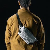 man on black studio background wearing white sling bag
