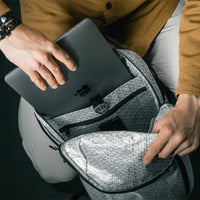 man placing laptop into sleeve inside white backpack