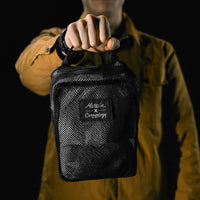 man on black studio background holding packed up white messenger bag in mesh bag