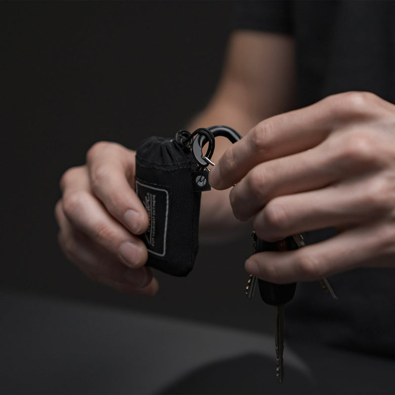 hands attaching carabiner to mini pocket blanket paracord loop