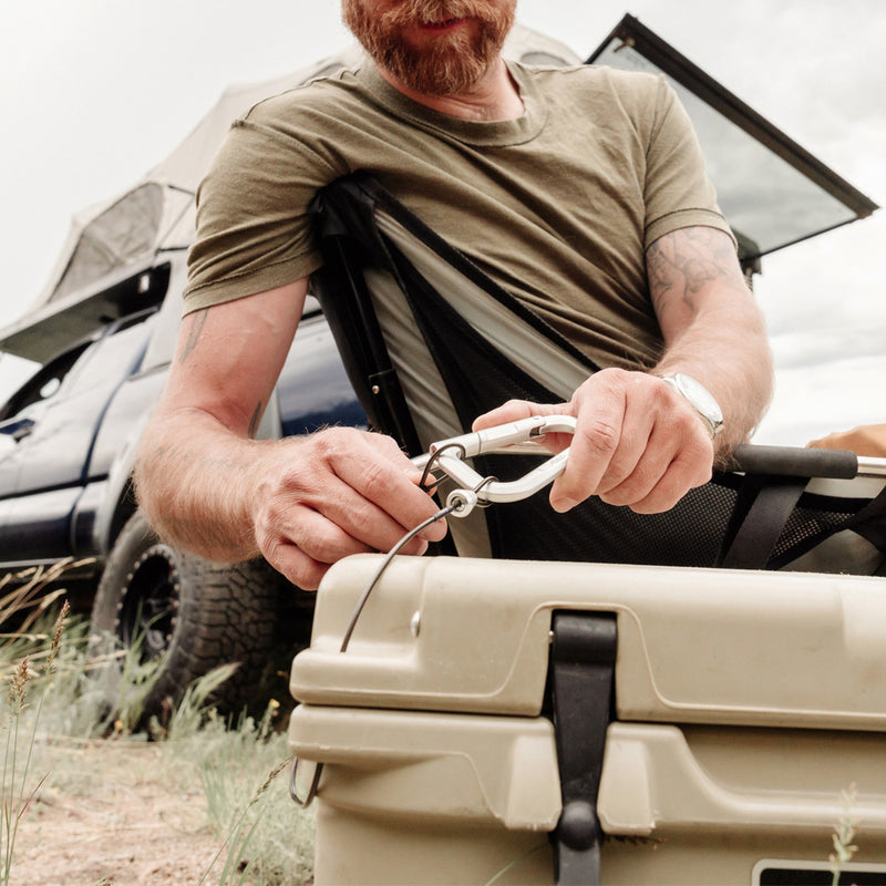 man overland camping, locking accessory cable around his cooler
