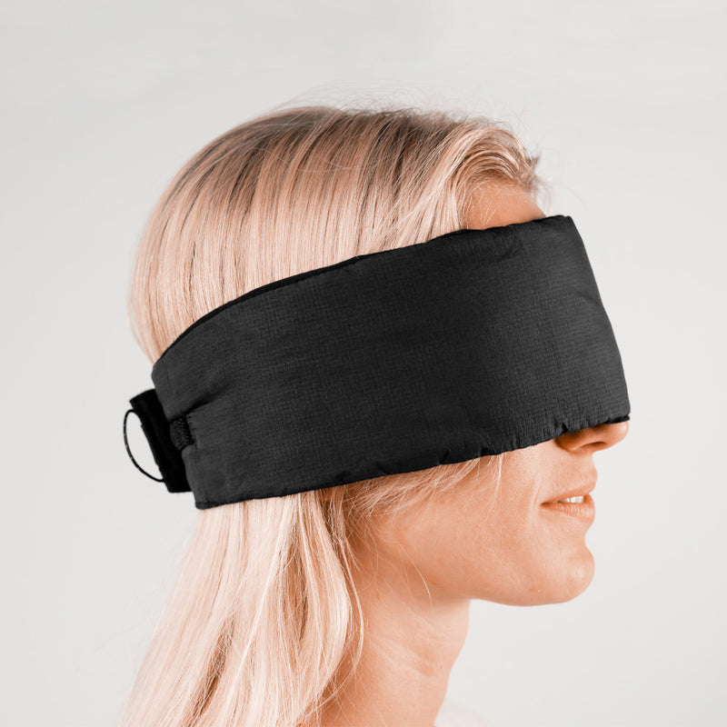 Side view of woman on light gray background, wearing fully secured eye mask around her head
