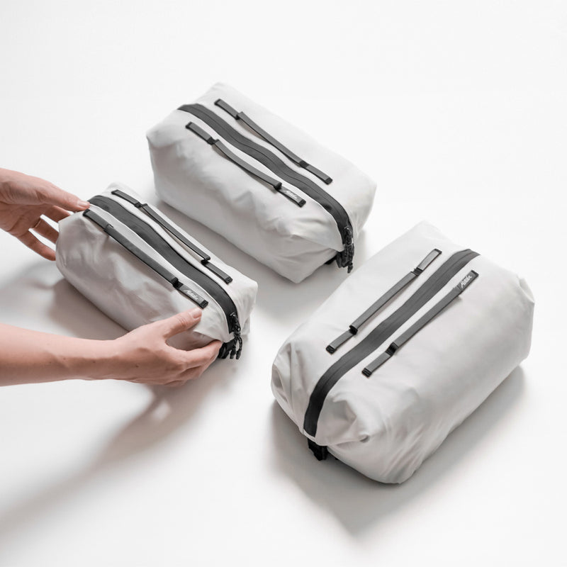 hands placing closed, compressed white gear cubes on white surface