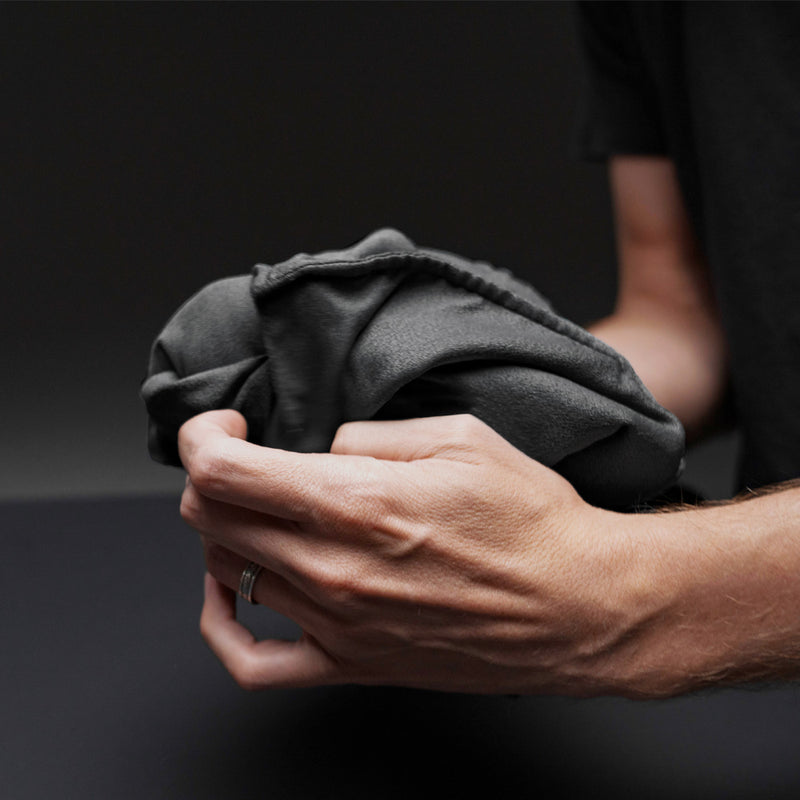 Hands folding charcoal beach towel into pocket