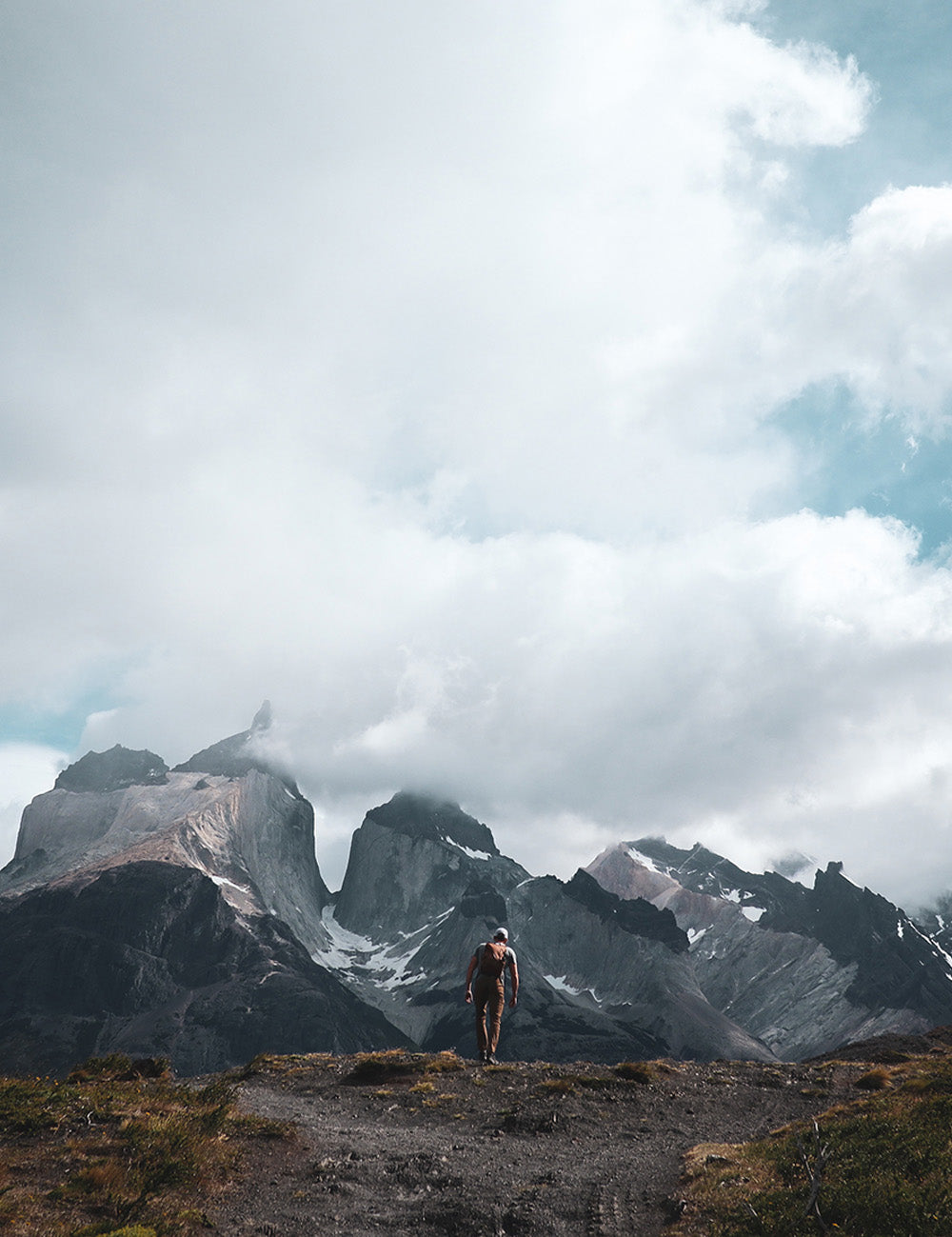 View of jagged mountains in the clouds with small man in front