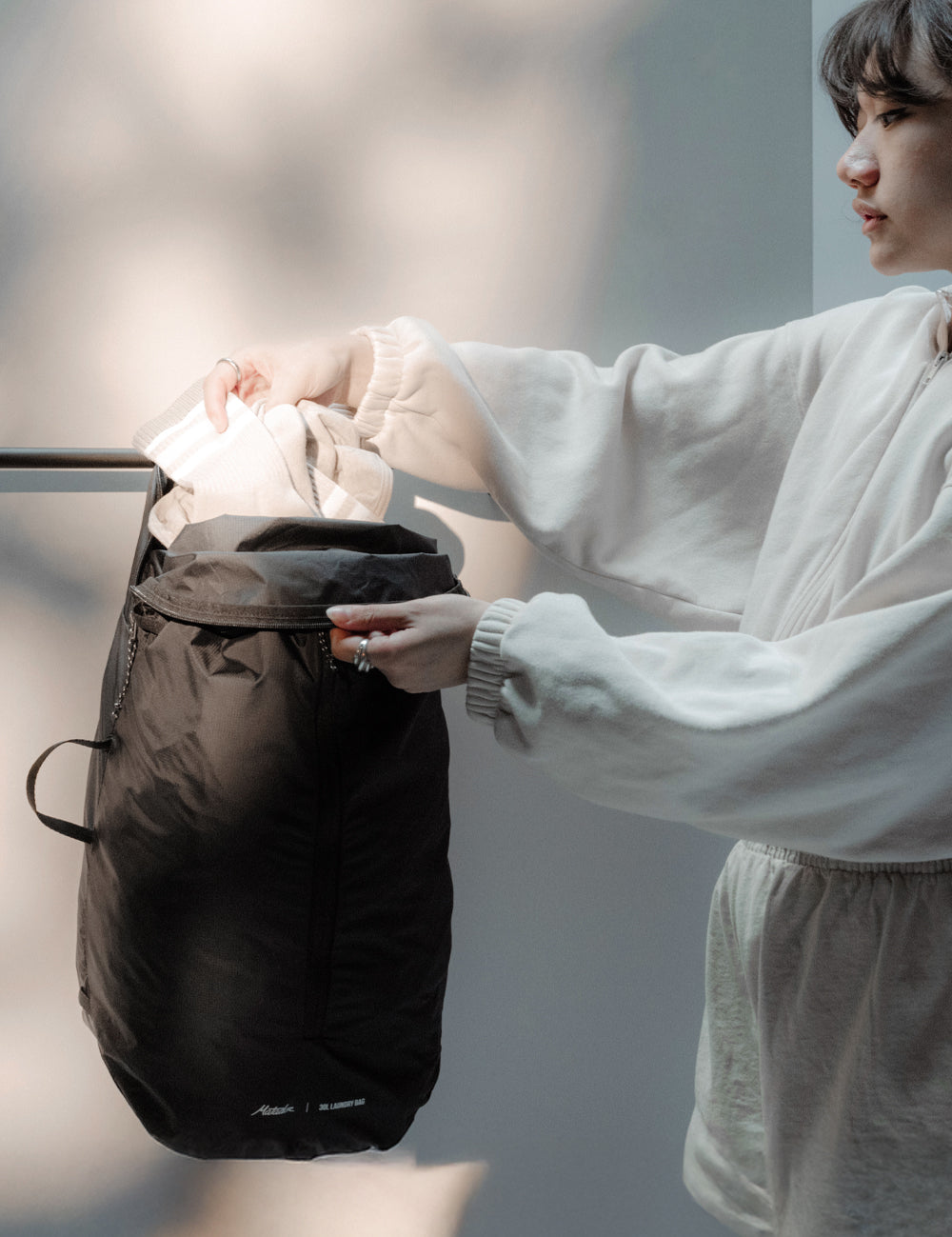 Woman placing laundry into hanging black laundry bag