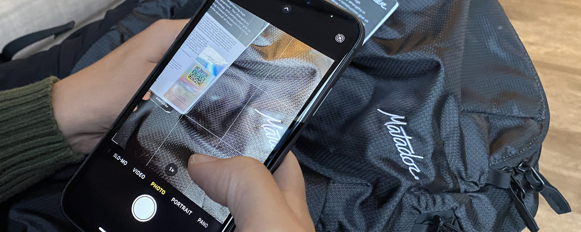 Hands holding cell phone, taking picture of authentication hologram on hang tag