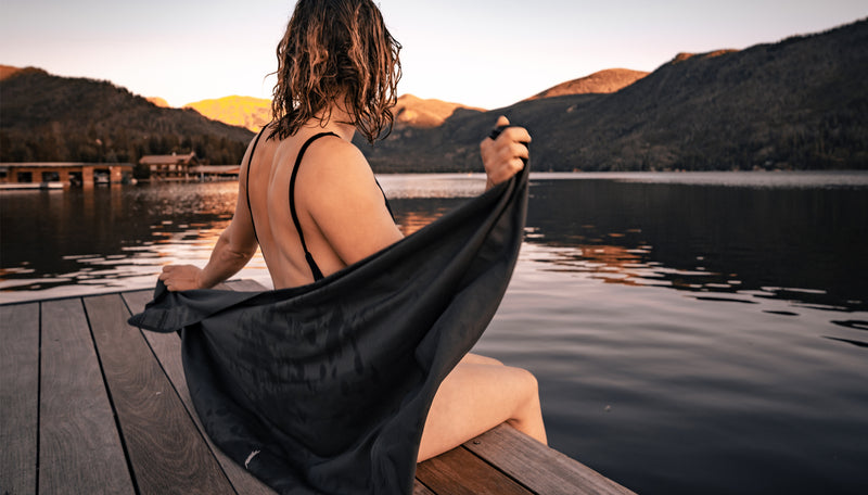 Woman at sunset lake, wrapping herself in a NanoDry towel