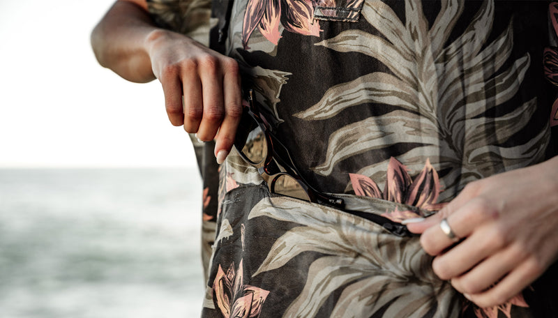 close up of hands pulling sunglasses out of marble floral poncho pouch