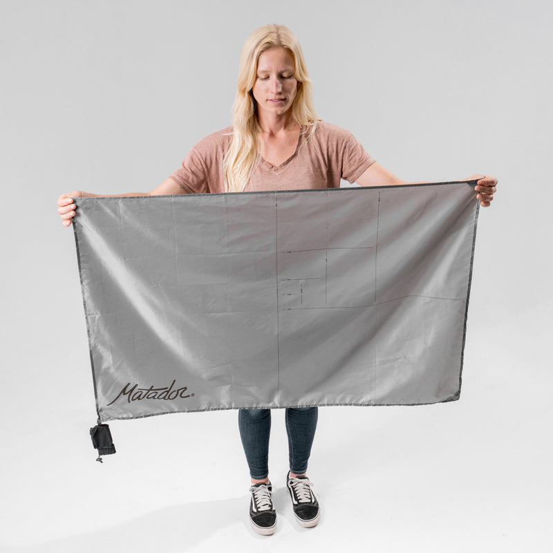 Woman standing in white photo studio, holding out the pocket blanket mini in front of her