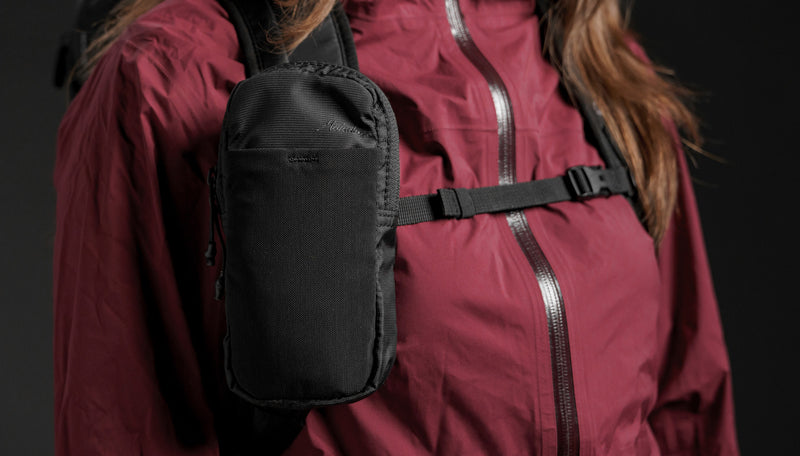 woman in burgundy jacket wearing speed stash on her backpack strap