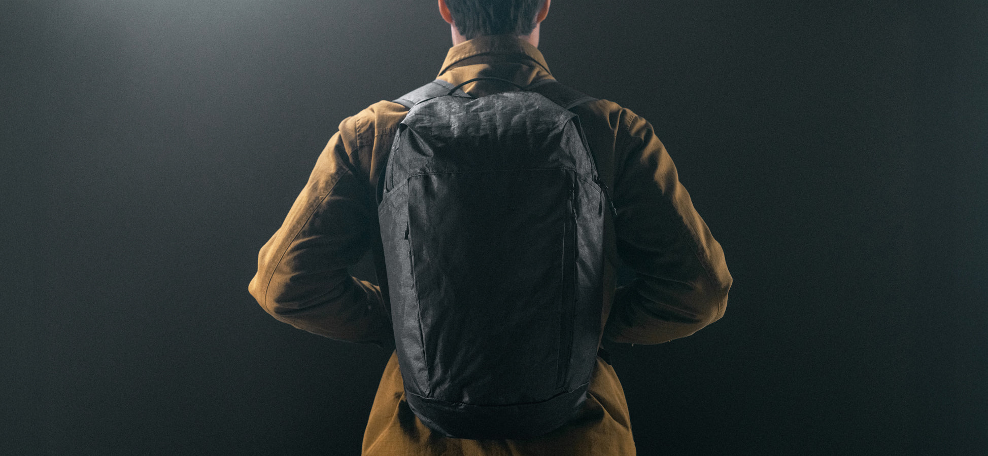 Man in black studio wearing black backpack