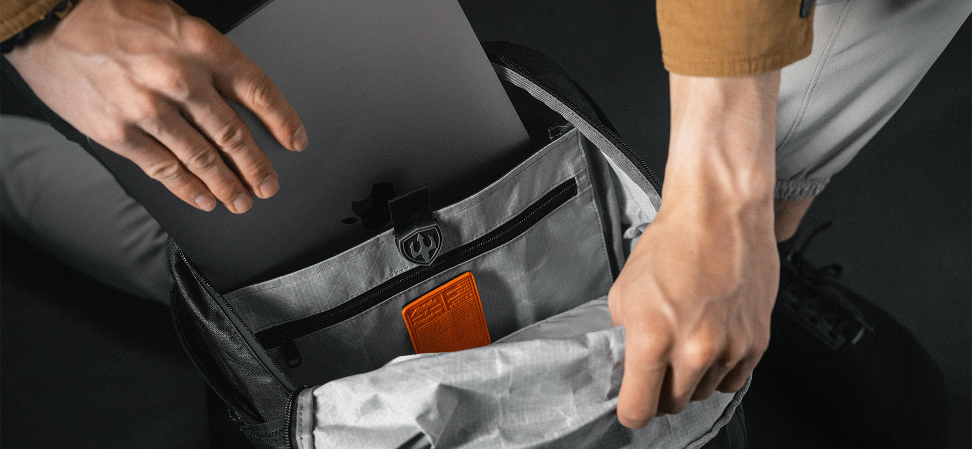 Man placing laptop into open backpack