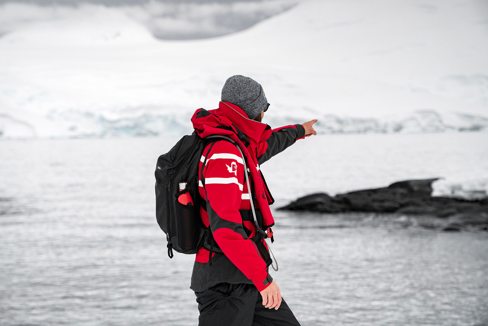 someone pointing at glaciers with a water-resistant backpack on in the winter