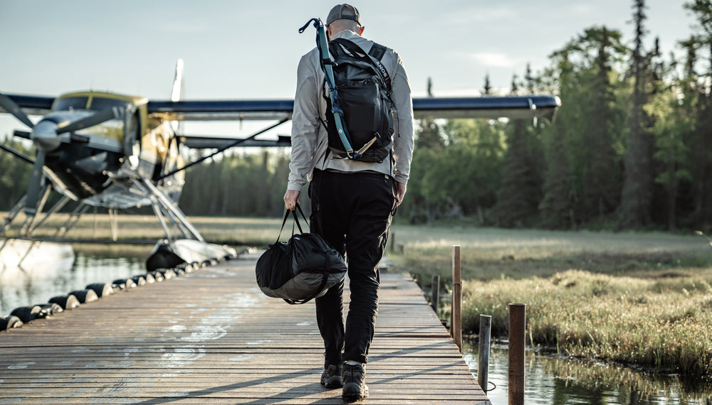 Man walking on dock, toward a sea plane, carrying the Freefly Duffle