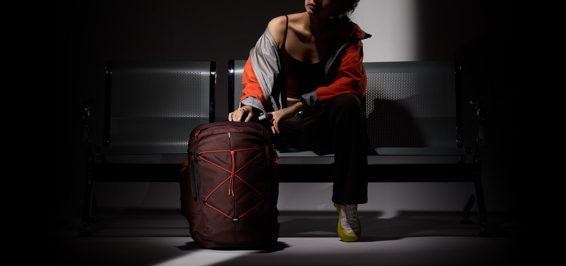 person sitting on moody lit bench with garnet back and orange accents