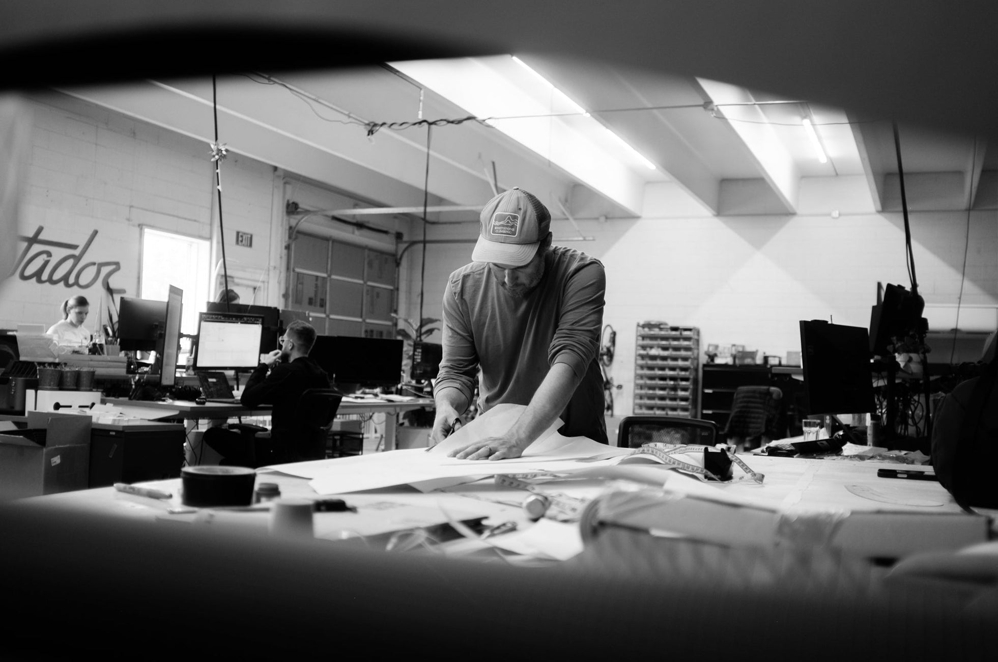 Person working at a desk in an office with cutting paper for a product design.