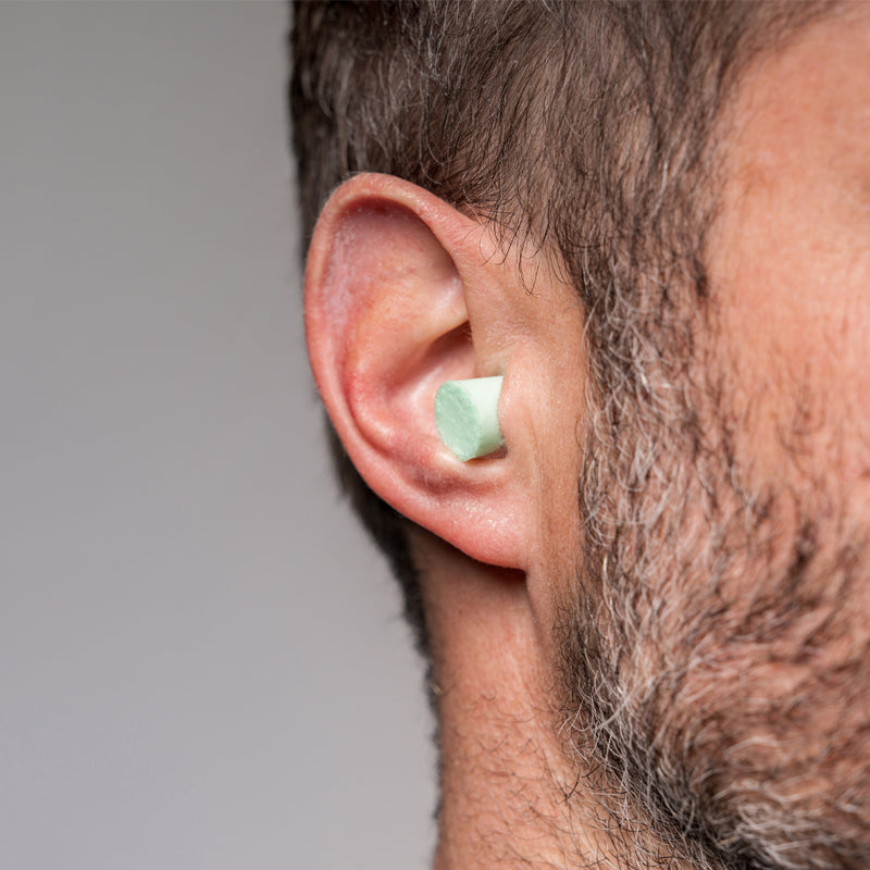 Close up view of mint colored ear plug in man's ear