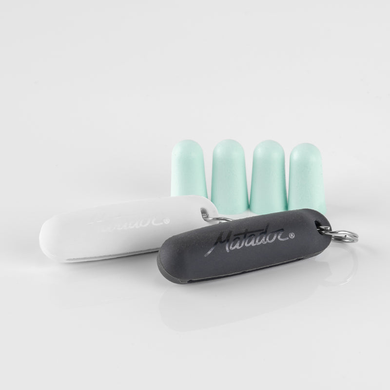 2 silicone earplug cases (white and black) and 4 mint earplugs sitting on a reflective, light gray background