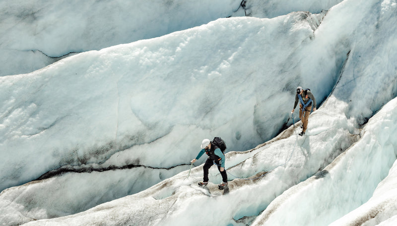 Two men with climbing ropes, traversing a glacier