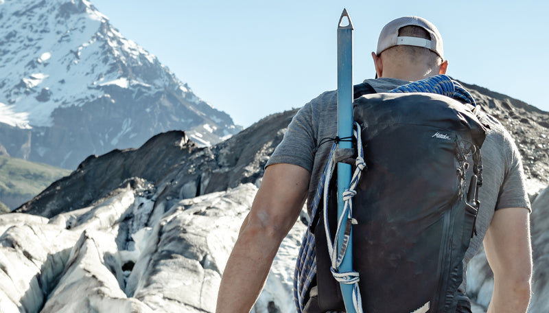 Man hiking snowy mountains, wearing Freerain28 backpack