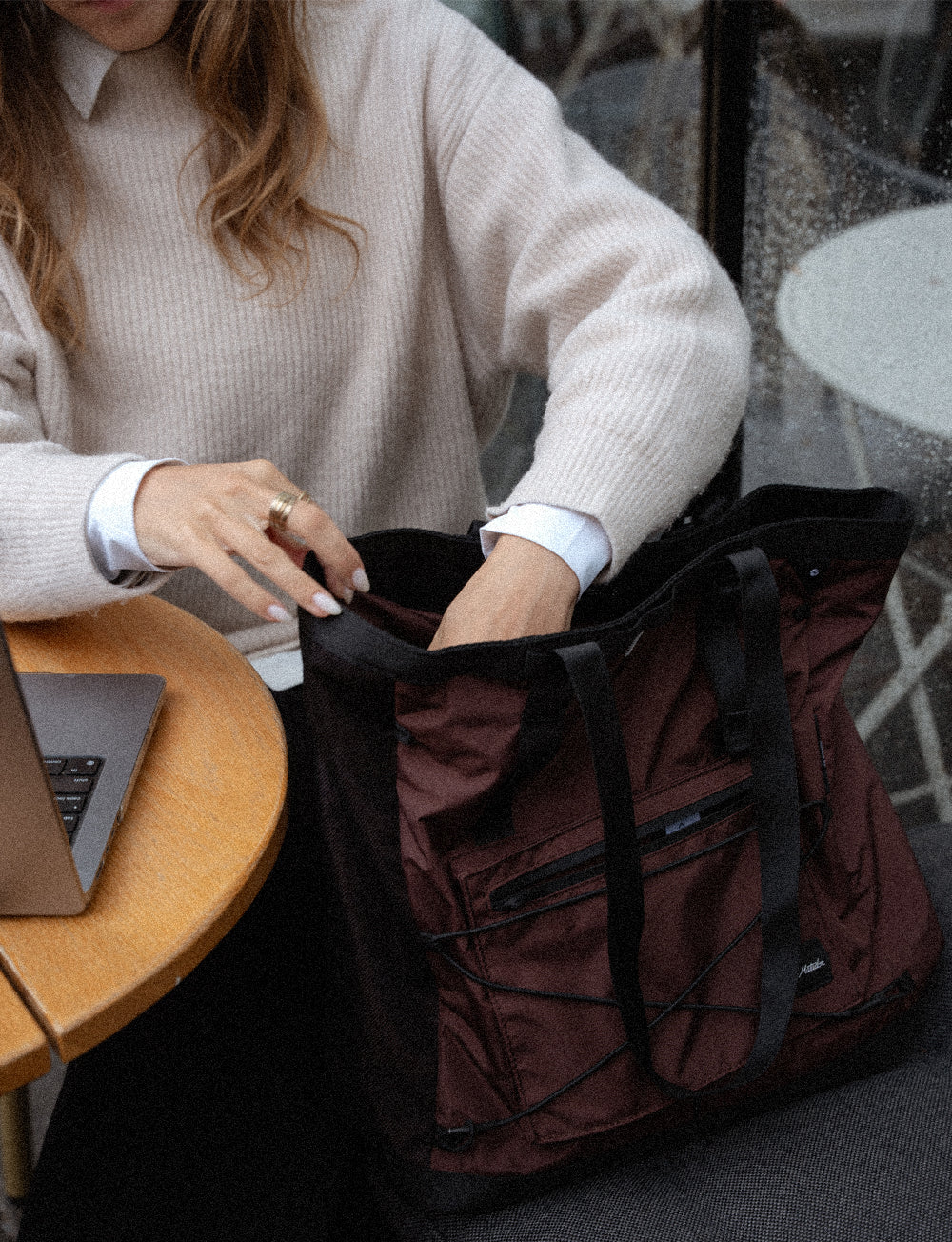 person at cafe table looking into garnet tote