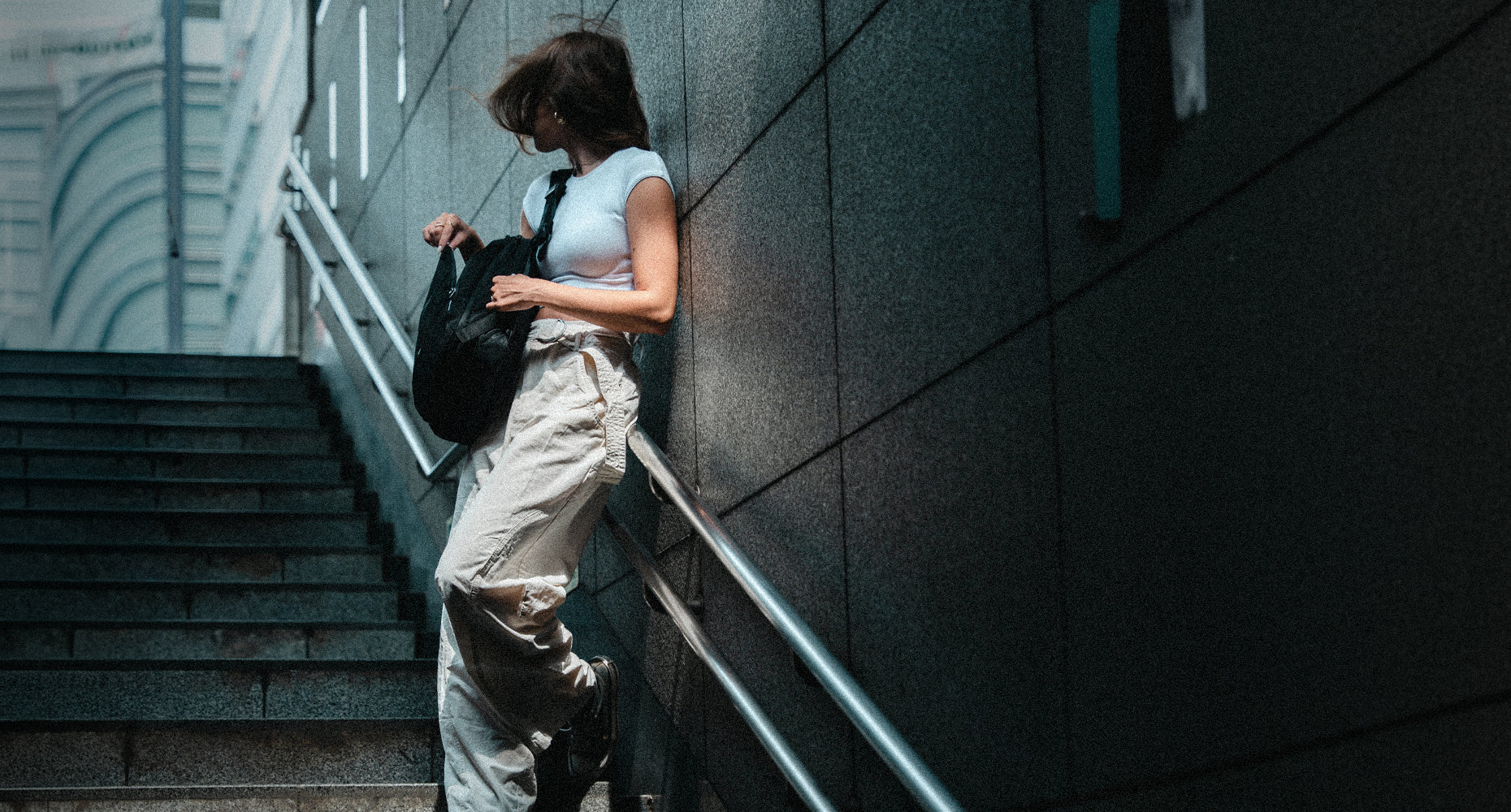 person in stairwell holding black backpack