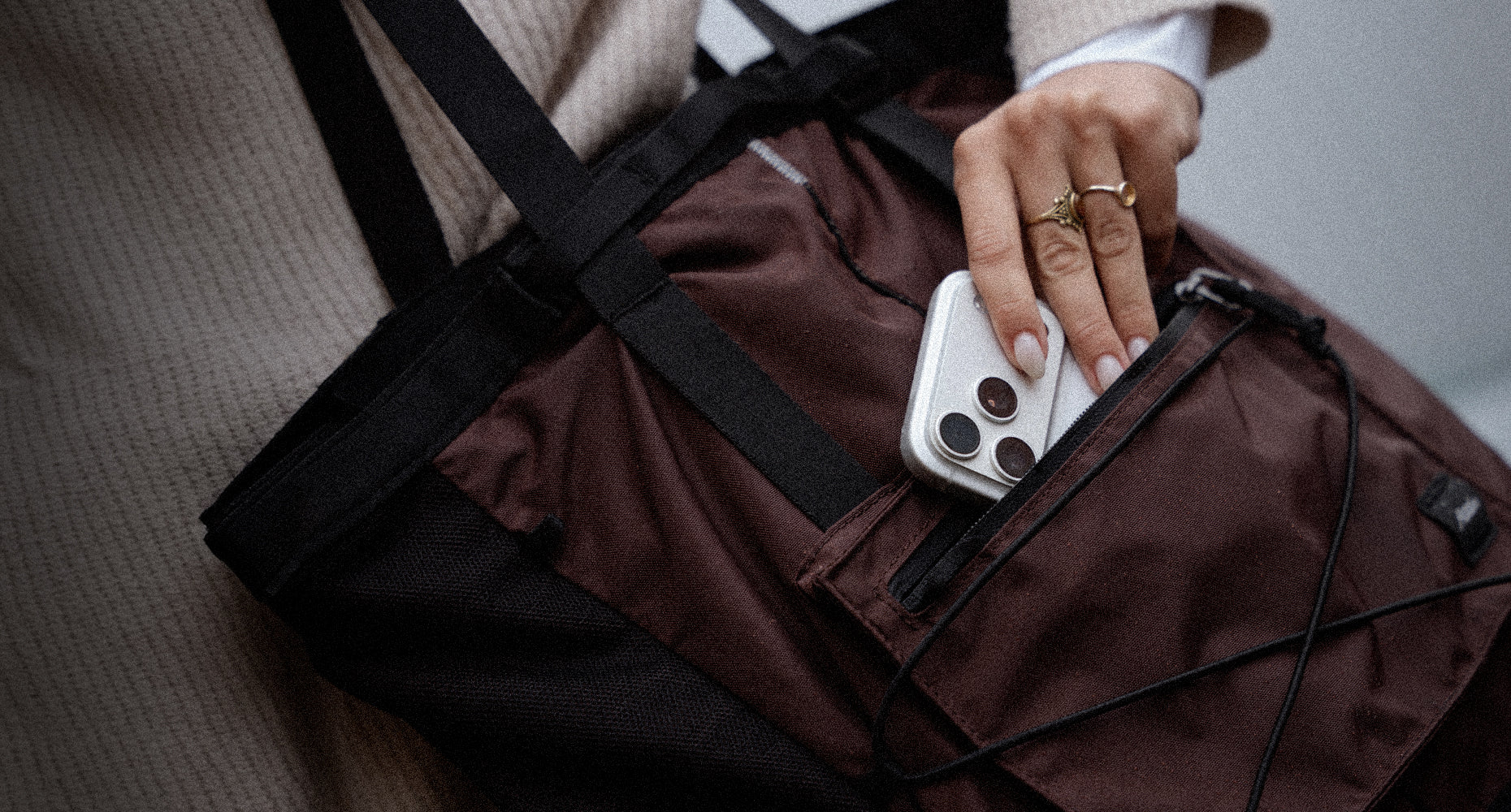 hand pulling phone out of garnet tote pack