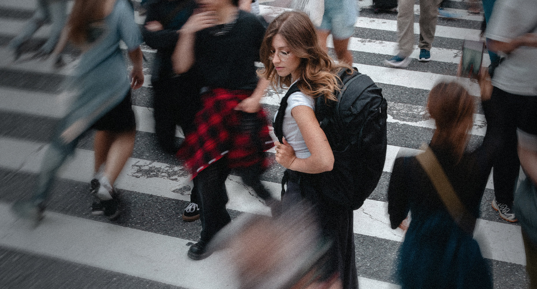 person in busy crosswalk with black backpack