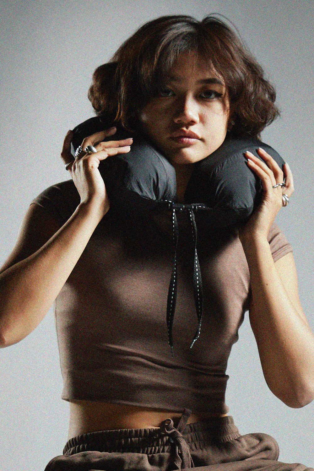 person in front of gray background holding neck pillow around their nect