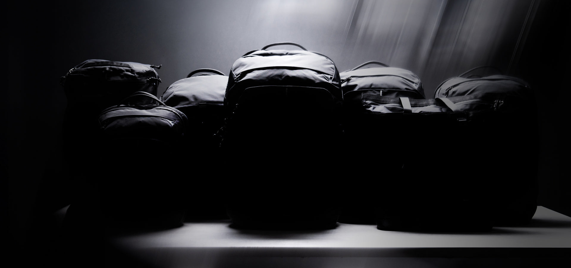 moody dark image of black bags under a spot light