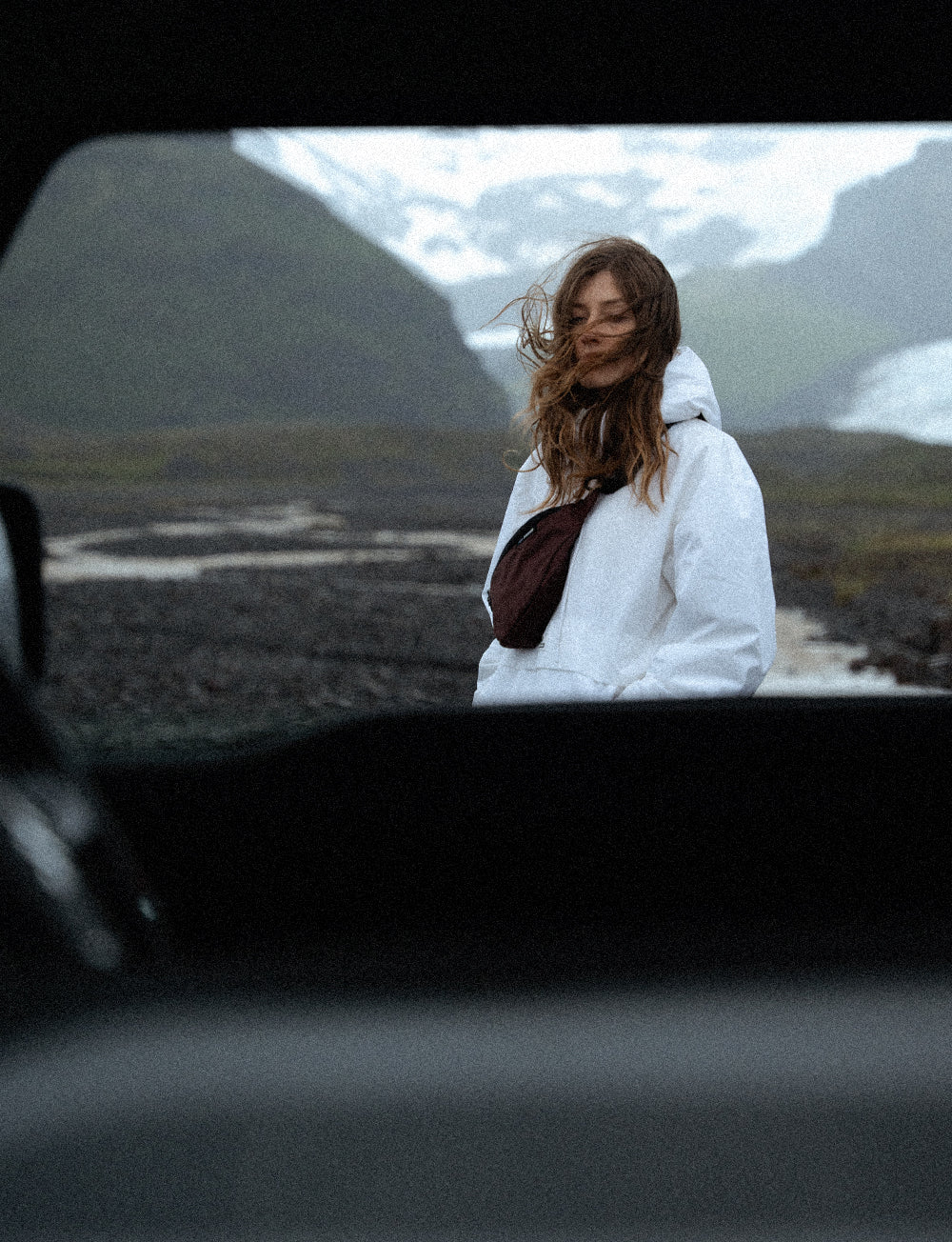 Person in Icelandic landscape wearing white jacket and garnet sling