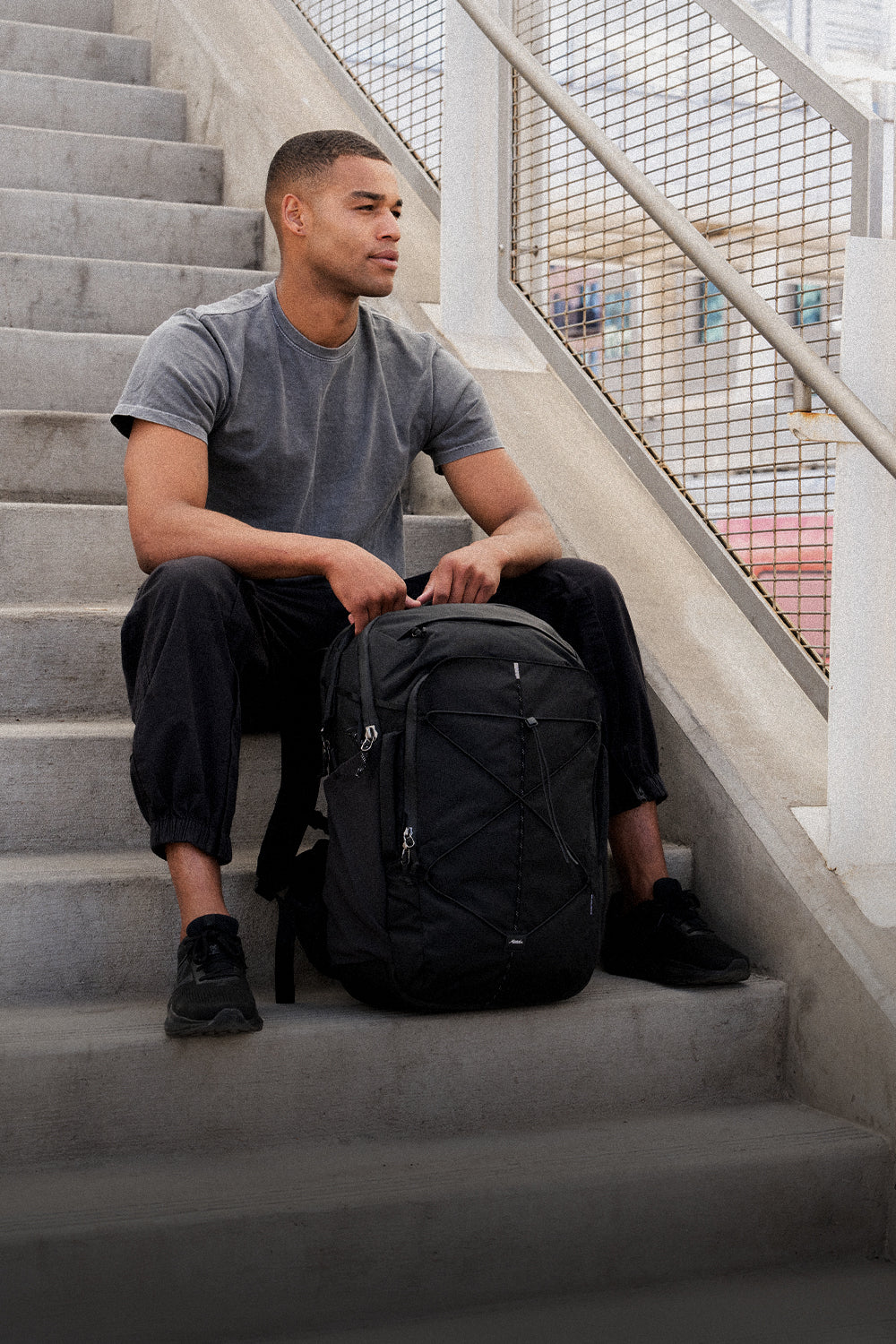 Person sitting on stairs with black backpack