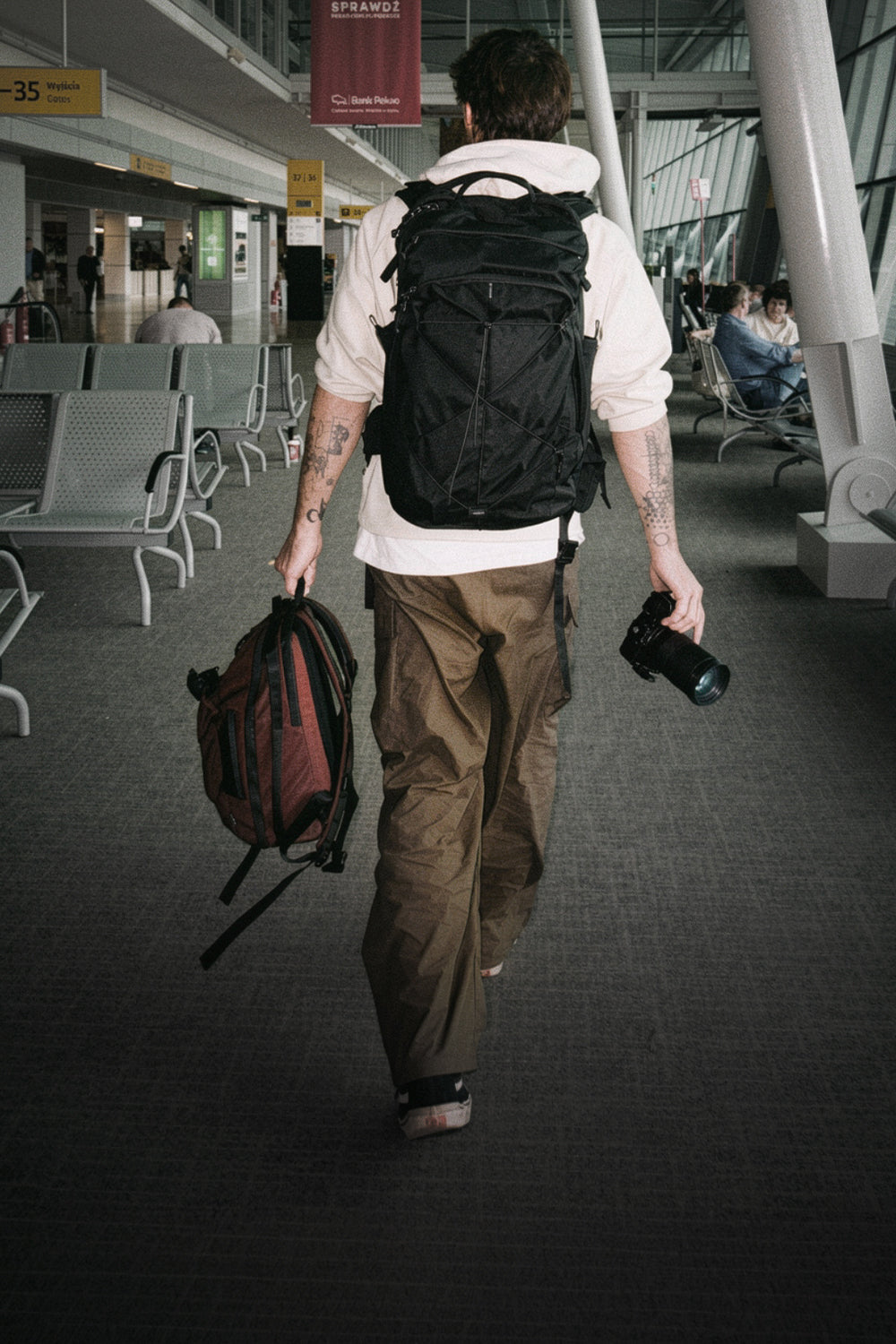 person walking through aiport with black backpack and camera
