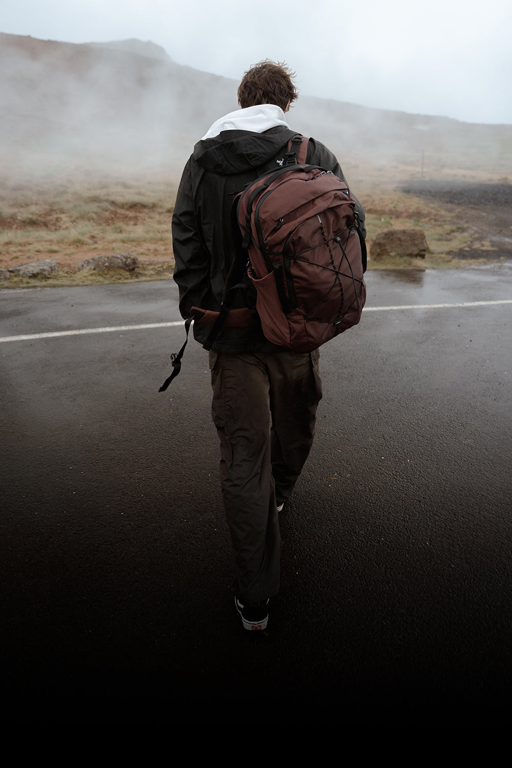person with garnet backpack walking in misty terrain