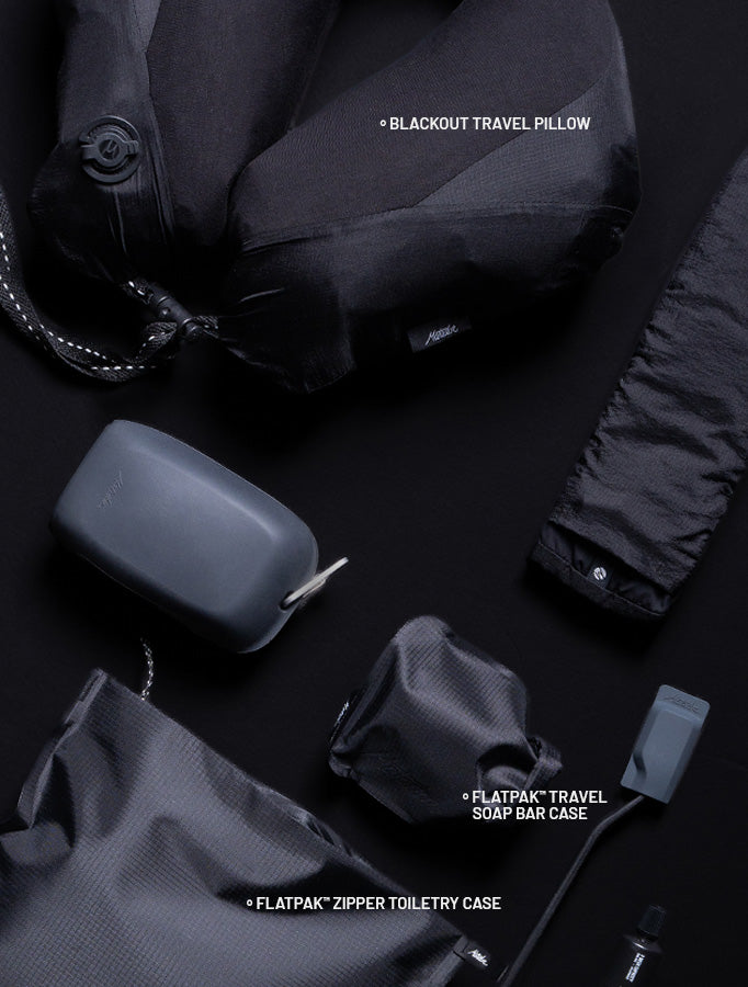various travel accessories on a black background labeled: blackout travel pillow, flatpak travel soap bar case, flatpak zipper toiletry case