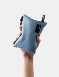 Hand holding a blue fabric pouch with a brand logo on a white background