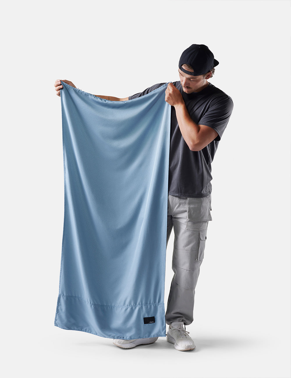 Man holding a light blue fabric against a white background