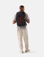 Man wearing a black backpack with orange accents on a white background