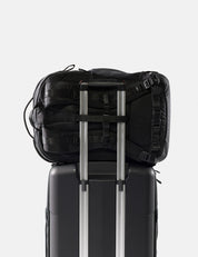 Black backpack on top of a black suitcase with a white background