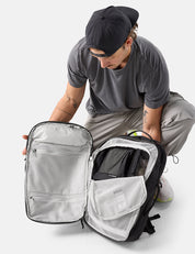 Person opening a black and gray backpack on a white background
