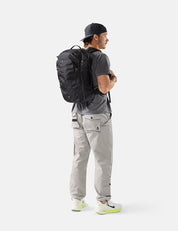 Person wearing a black backpack and gray pants on a white background